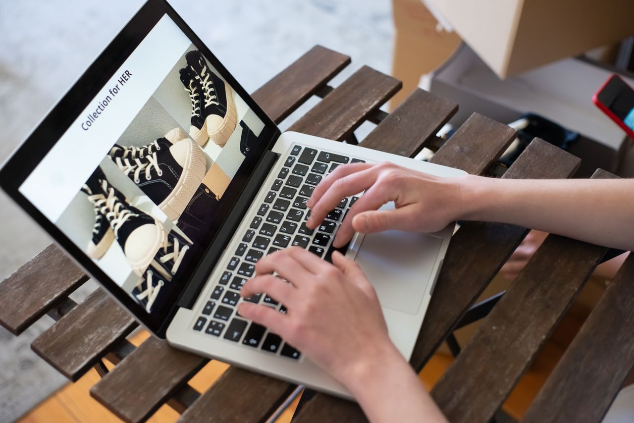 creative Hands of a person browsing a Collection for HER on an online shoe store using a laptop.