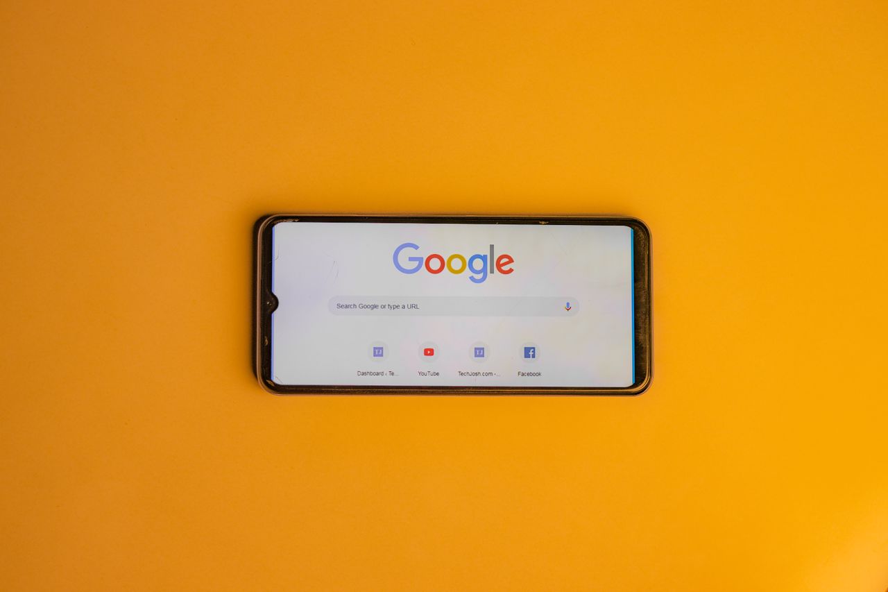 Services-02 Smartphone displaying Google search page on a vibrant yellow background.
